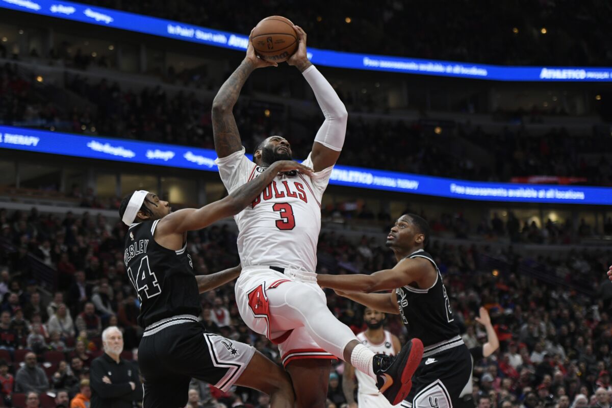 Andre Drummond (3), de los Bulls de Chicago, descuelga un rebote en contra de Blake Wesley (14) y Malaki Branham, derecha, de los Spurs de San Antonio, durante la segunda mitad del juego de baloncesto de la NBA, el lunes 6 de febrero de 2023, en Chicago. (AP Foto/Paul Beaty)