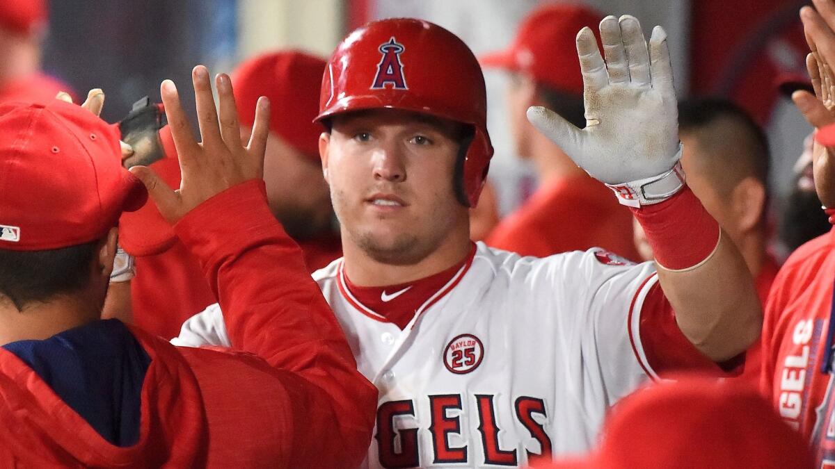 Angels outfielder Mike Trout gets high-fives in the dugout after scoring a run against the Texas Rangers on Aug. 21.