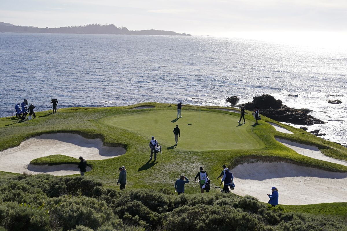 Tom Hoge, top center, walks to his ball on the seventh green of the Pebble Beach Golf Links during the first round of the AT&T Pebble Beach Pro-Am golf tournament in Pebble Beach, Calif., Thursday, Feb. 3, 2022. (AP Photo/Eric Risberg)
