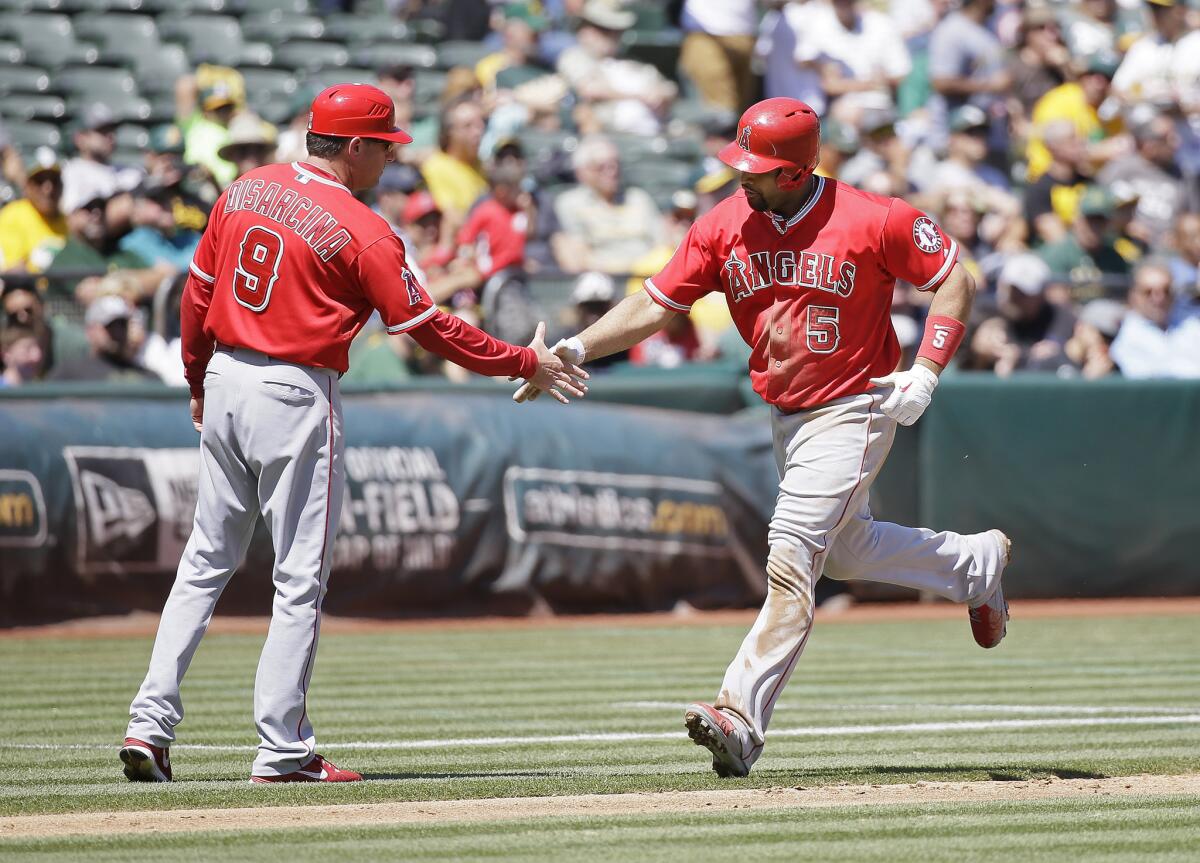 Los Angeles Angels' Albert Pujols, right, is greeted by third base coach Gary DiSarcina, left, after hitting a two-run home run off Oakland Athletics starting pitcher Sonny Gray in the second inning of their baseball game Wednesday, Sept. 2, 2015, in Oakland, Calif. Los Angeles won the game 9-4. The home run was Pujols' 35th of the season and the 555th of his career. (AP Photo/Eric Risberg)
