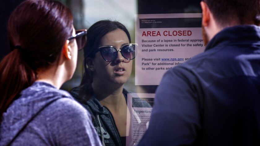 Visitors read a closure notice posted on the doors of Joshua Tree National Park Visitor Center on Saturday. The park was open but its visitors center and other facilities were closed because of a partial government shutdown.