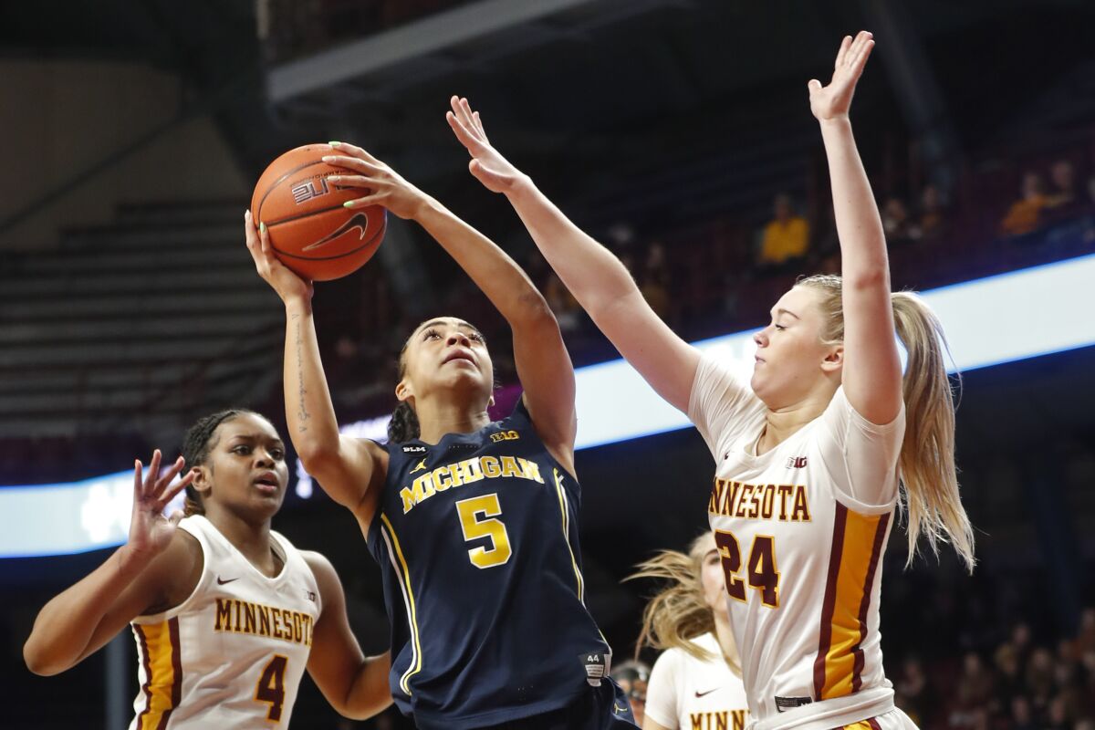 Michigan guard Laila Phelia (5) goes to the basket between Minnesota forwards Alanna Micheaux (4) and Mallory Heyer (24) in the third quarter of an NCAA college basketball game Sunday, Jan. 29, 2023, in Minneapolis. (AP Photo/Bruce Kluckhohn)
