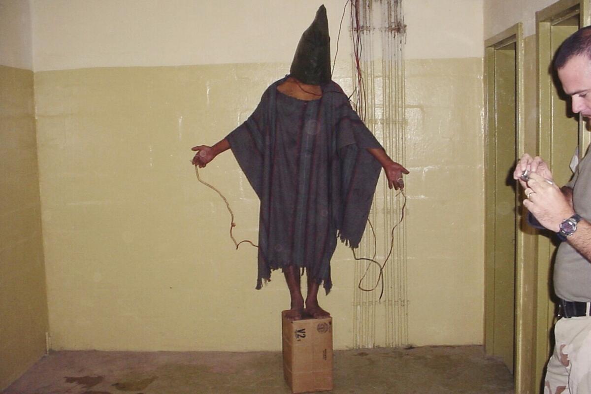 A detainee stands on a box with a bag on his head and wires attached to him in Abu Ghraib prison in Baghdad, Iraq. 