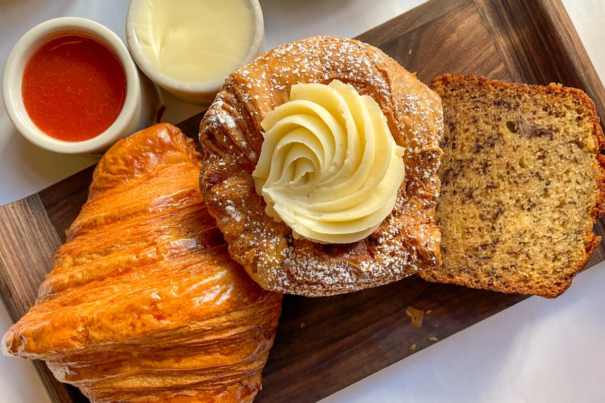 Morning pastries on a wooden board with two cups of sauce