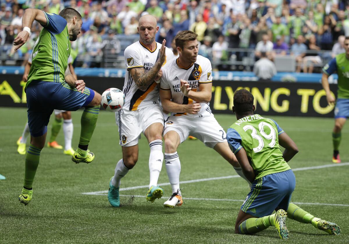 Galaxy's Dave Romney, center right, and Jelle Van Damme block a kick by Seattle's Clint Dempsey, left.