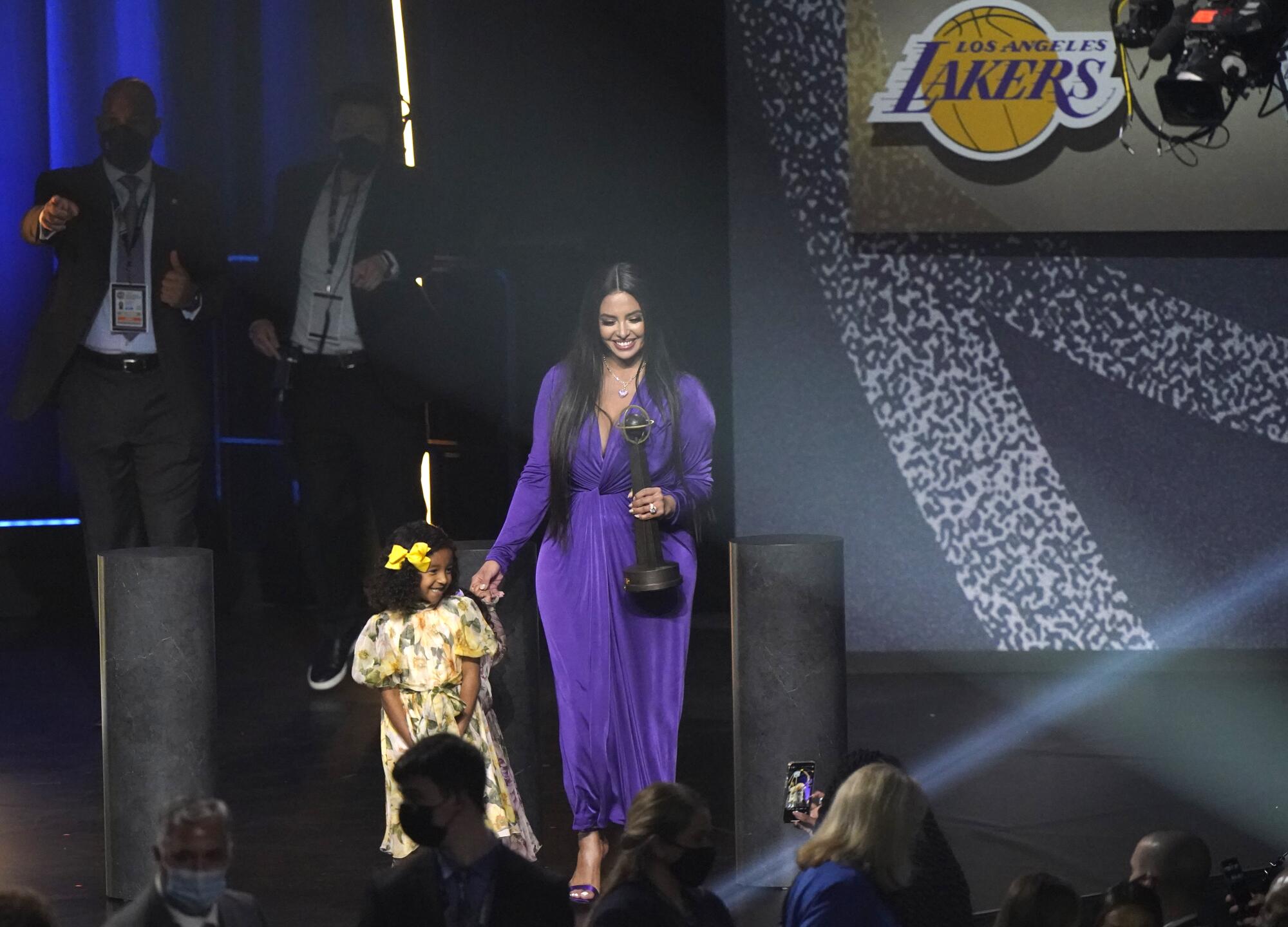Bianka Bryant smiles for the crowd as her mother, Vanessa, holds Kobe Bryant's Hall of Fame trophy.