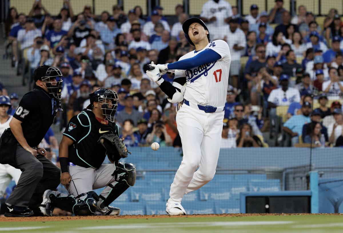 El jugador designado de los Dodgers, Shohei Ohtani, suelta un grito mientras desvía una pelota que estaba en su pierna