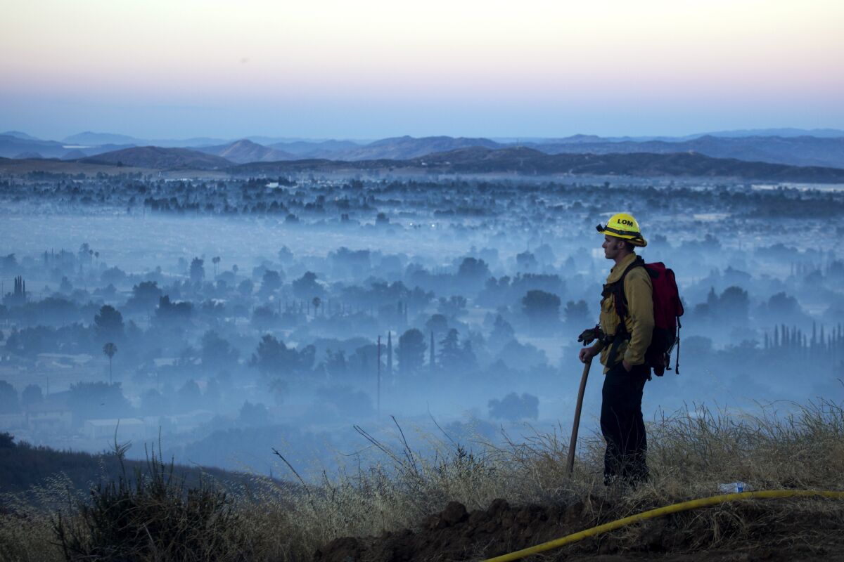 FILE - In this Aug. 1, 2020, file photo, a firefighter watches a brush fire at the Apple Fire in Cherry Valley, Calif. La Nina, which often means a busier Atlantic hurricane season, a drier Southwest and perhaps a more fire-prone California, has popped up in the Pacific Ocean, the National Oceanic and Atmospheric Administration announced Thursday, Sept. 10. (AP Photo/Ringo H.W. Chiu, File)