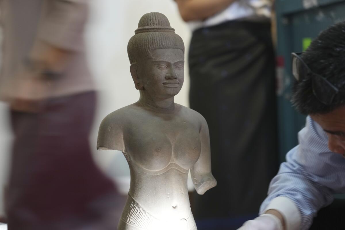 Unidentified people swirl around a rare Angkor-era sculpture in Cambodia. 