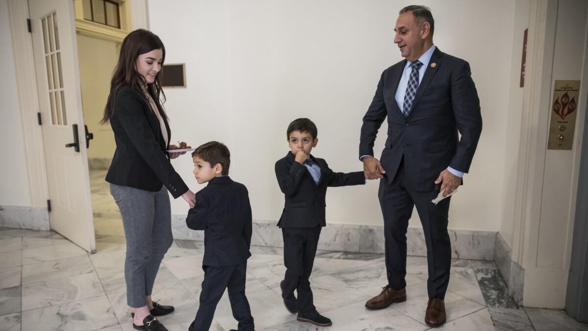 Rep. Gil Cisneros (D-Yorba Linda), with aide Annie Campbell and his twin sons Alexander, second from left, and Christopher, walk to the swearing-in ceremony for House members.