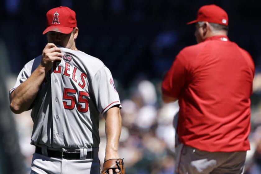 Angels starter Joe Blanton, left, heads to the dugout after being pulled out of the game by Manager Mike Scioscia during the fifth inning of the Angels' 4-3 loss Sunday to the Seattle Mariners.