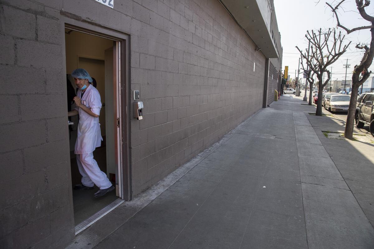 An employee at Rockenwagner Bakery heads back into the building after ordering food from a taco truck parked on West Adams Blvd. on Saturday, April 4, 2020 in West Adams, CA. (