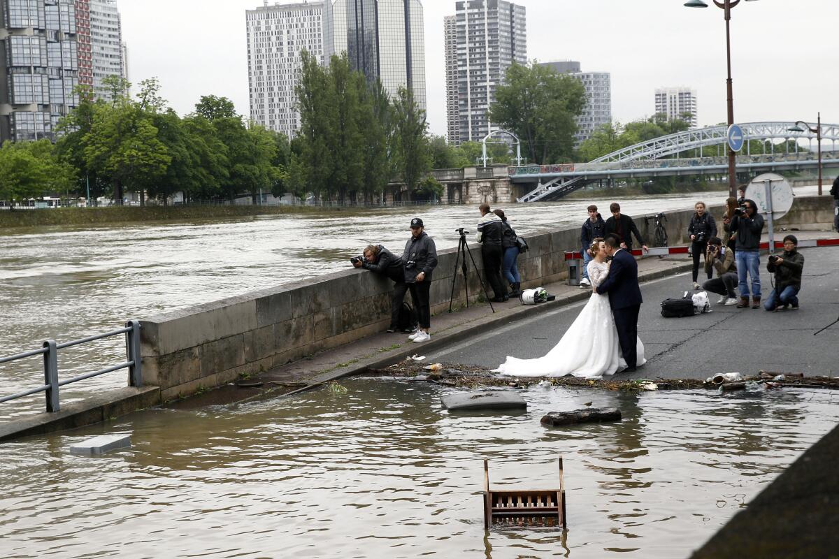 A married couple poses in front of the flooded banks of the River Seine