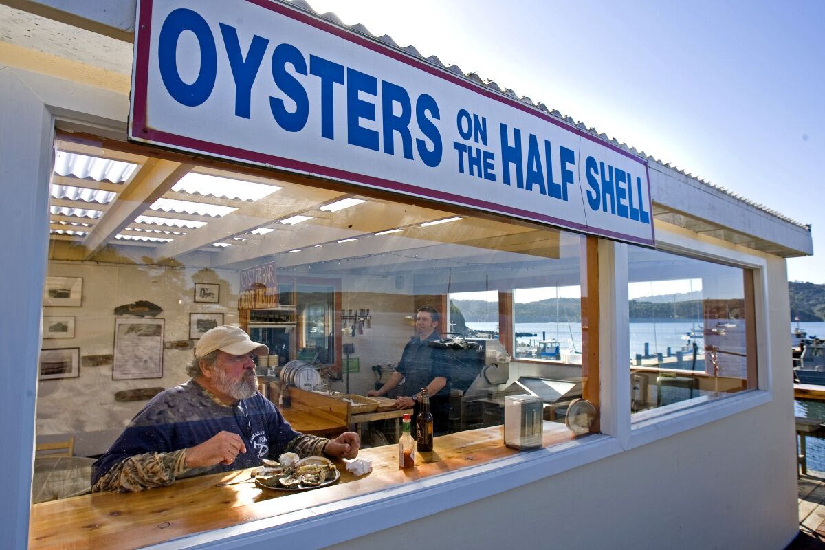 A man sits at a window counter eating from a platter of oysters at the Marshall Store.