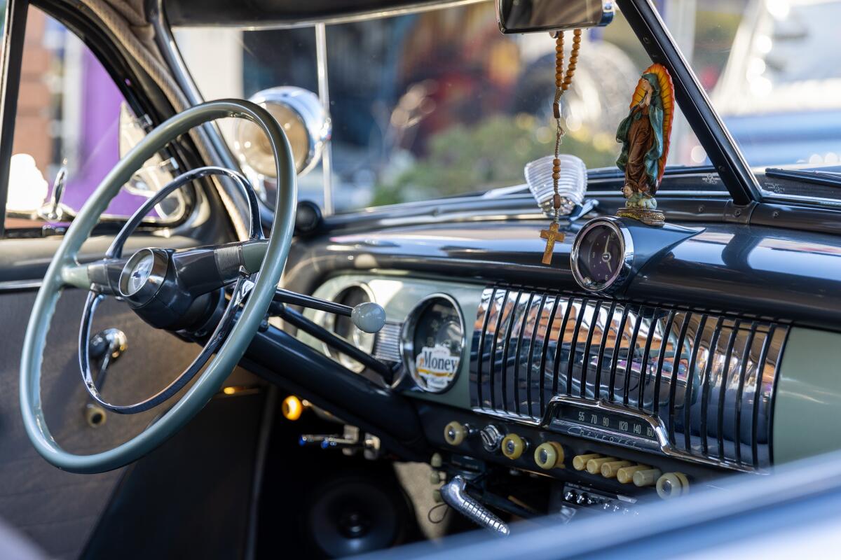 The inside of a classic car on display shows a rosary hanging from the rear view mirror.