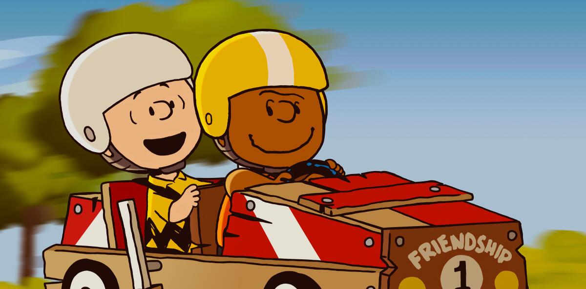 Charlie Brown and Franklin Armstrong in helmets sit in a soap box derby car.