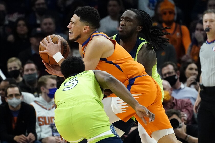 Phoenix Suns guard Devin Booker is pressured by Minnesota Timberwolves guard Malik Beasley (5) during the first half of an NBA basketball game, Friday, Jan. 28, 2022, in Phoenix. (AP Photo/Matt York)