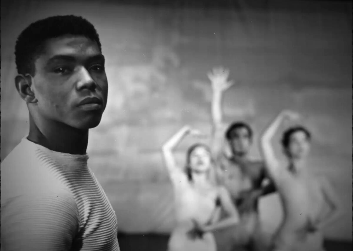 A young man with three dancers in the background from the documentary "Ailey." 
