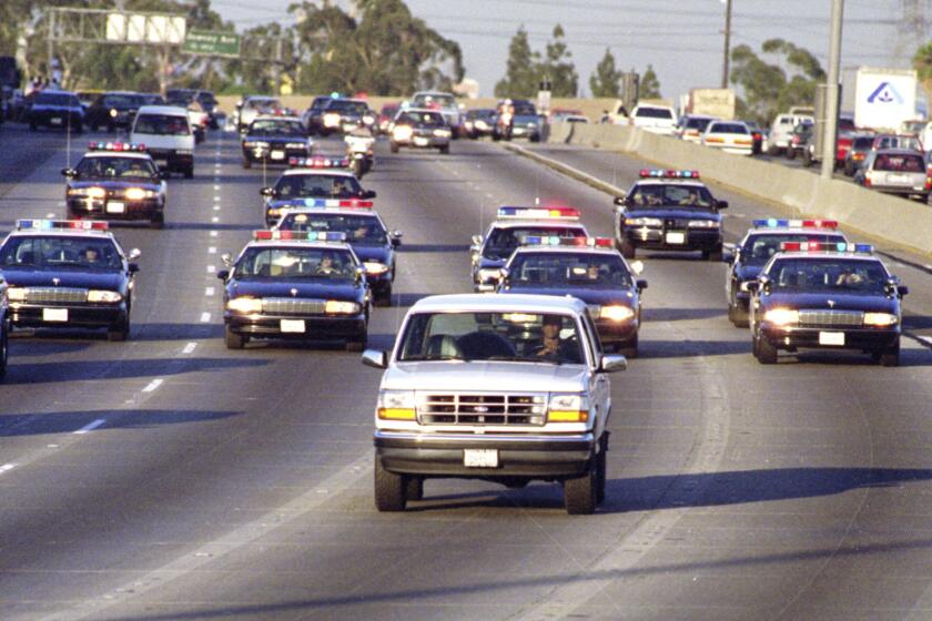 California Highway Patrol officers chase Al Cowlings, driving, and O.J. Simpson, hiding in the rear of a white Ford Bronco, on the 91 Freeway.