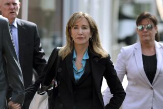 Felicity Huffman in a blue suit shirt and a black suit walking with two people in business attire on either side