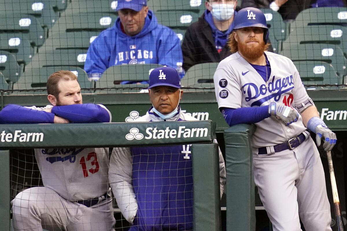Unhappy-looking Dodgers players flank manager Dave Roberts as they watch a game