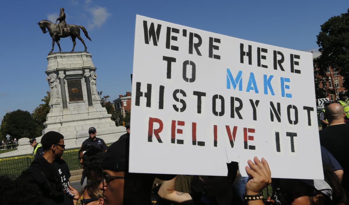 Protesters hold signs in front of the statue of Confederate General Robert E. Lee