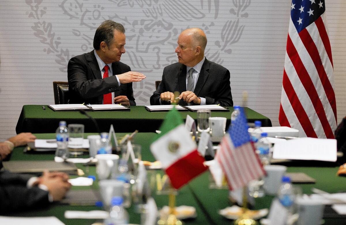 California Gov. Jerry Brown, right, talks with Mexico Energy Secretary Pedro Joaquin Coldwell before they sign a memorandum of understanding in Mexico City on Tuesday. Before his trip to Mexico this week, Brown had said little on the border crisis.