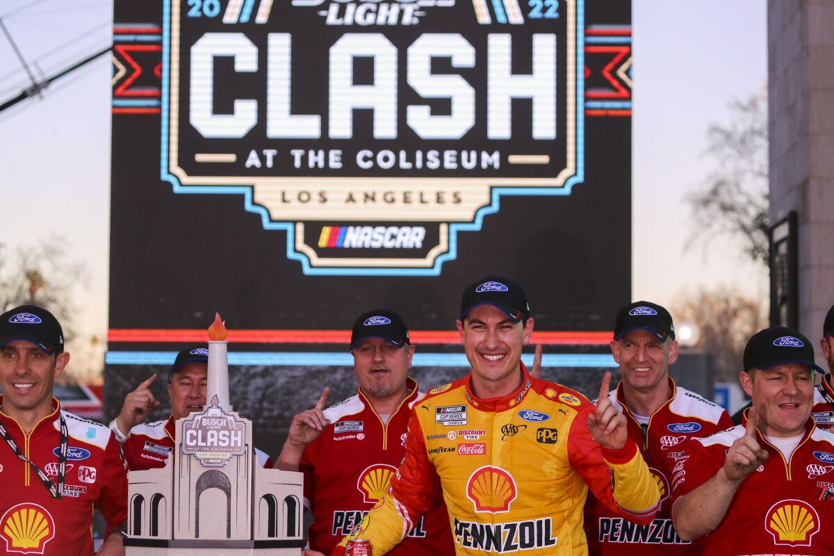 NASCAR driver Joey Logano takes photos with his crew and trophy after he won the Busch Light Clash at the Coliseum.