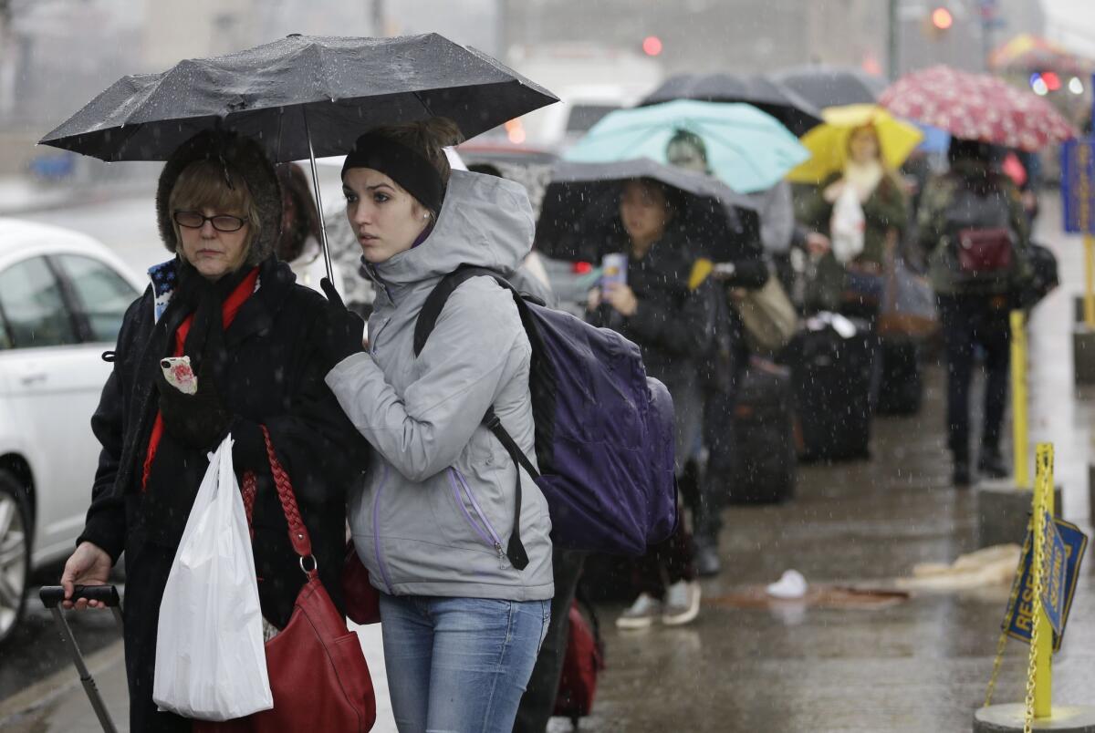 Travelers wait in the rain in New York to board a bus for Washington, D.C., on Dec. 24. Christmas Eve was shaping up to be windy, wet and warm instead of white across much of the country.