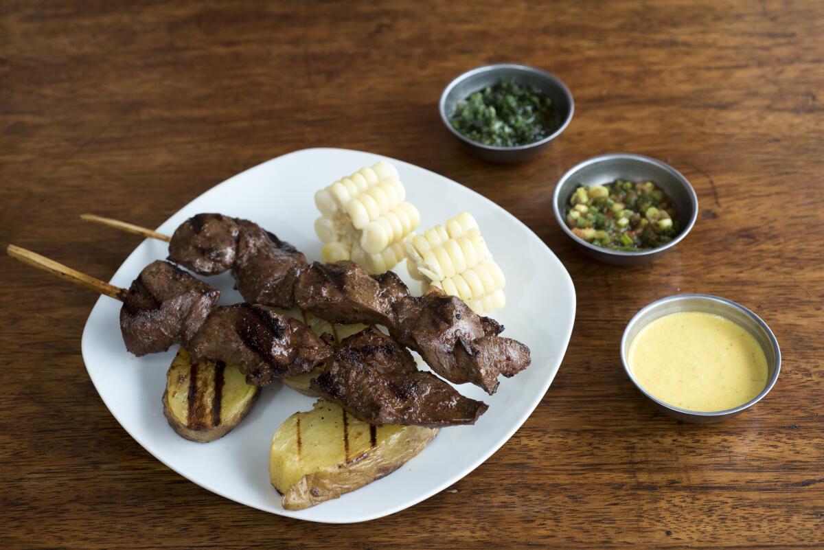 Anticuchos is popular in Peruvian cuisine: Grilled skewered beef heart meat with boiled potato and white corn.