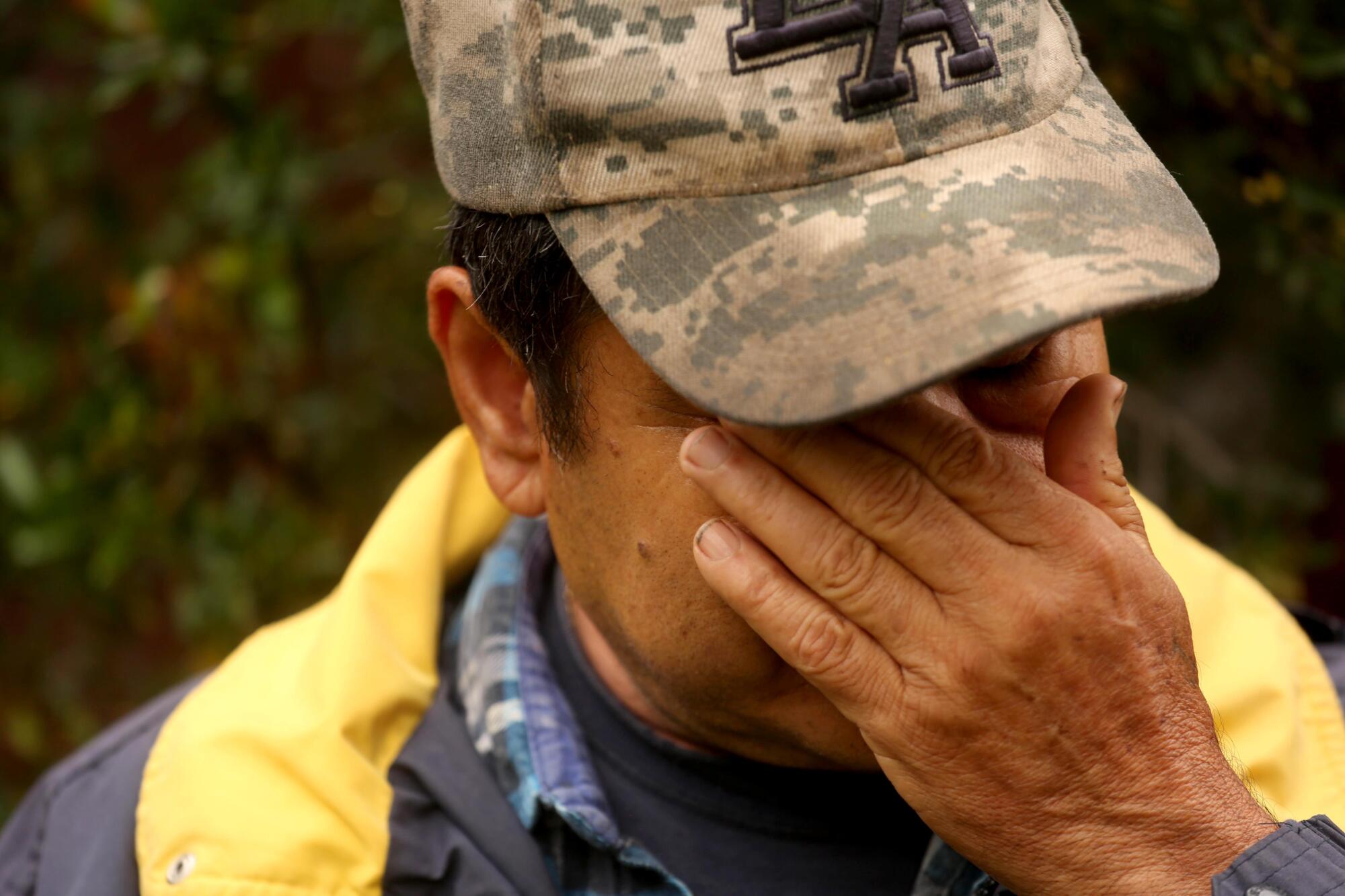 A man covers his face with his hand as he cries.