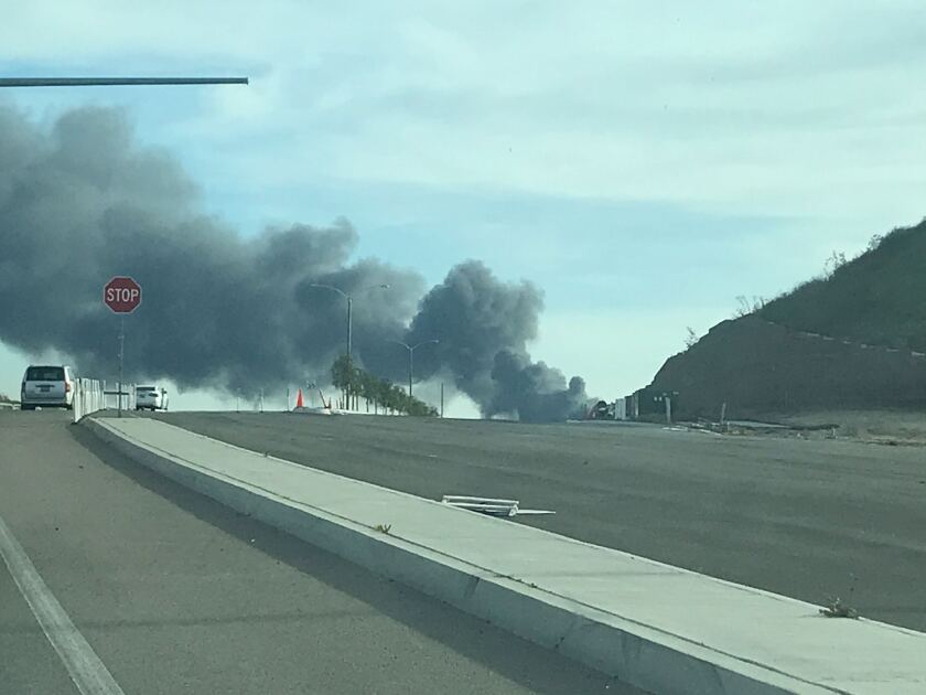 A fire at an auto wrecking yard in Otay Mesa spews black smoke into the air Wednesday afternoon.