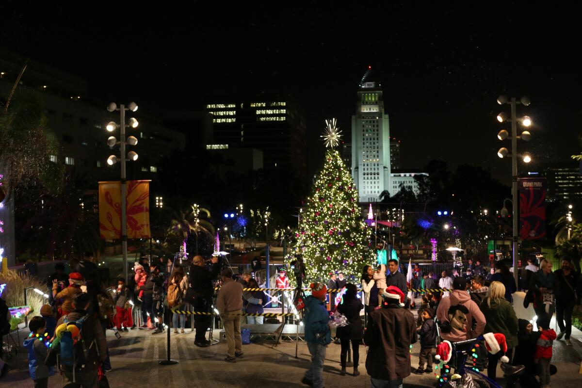 People gather around a large lighted tree.