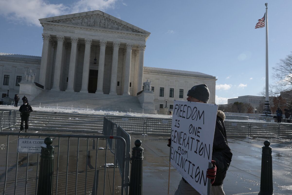  A protester holds a sign that reads "Freedom is one generation from Extinction" as he walks by the U.S. Supreme Court 