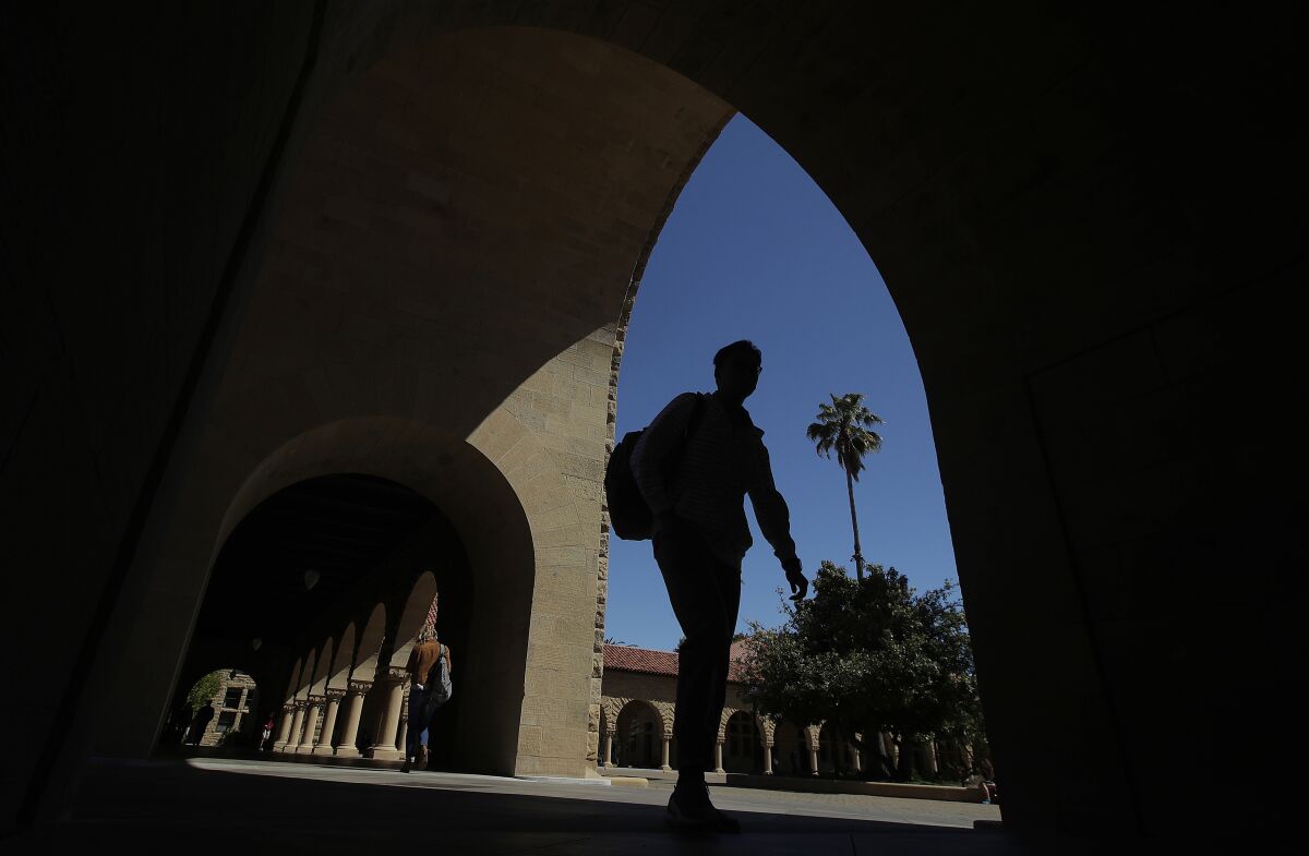FILE - In this April 9, 2019, file photo, pedestrians walk on the campus at Stanford University in Stanford, Calif. Thousands of public servants who were rejected from a student loan forgiveness program will get their cases reviewed by the Education Department as part of a new settlement in a lawsuit brought by one of the nation's largest teachers unions. (AP Photo/Jeff Chiu, File)