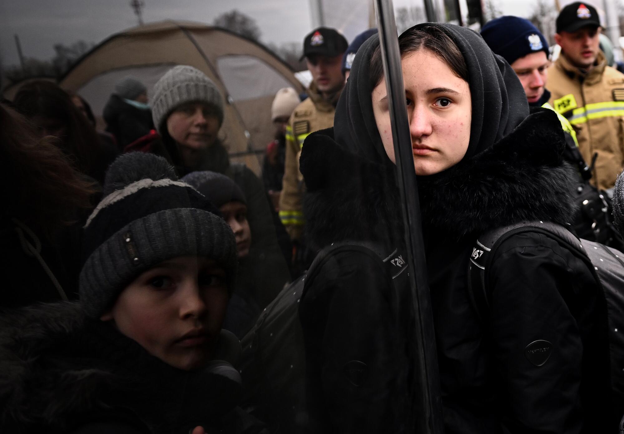 Ukrainian refugees board a bus after crossing the border in Medyka, Poland 