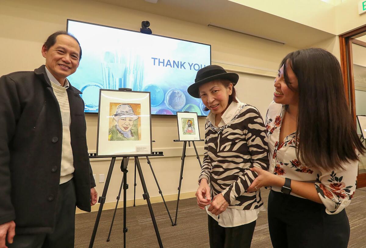 Participant artist Ngoclan Huang, center, stands next to her self-portrait with husband Joe and daughter Jessica, from left.