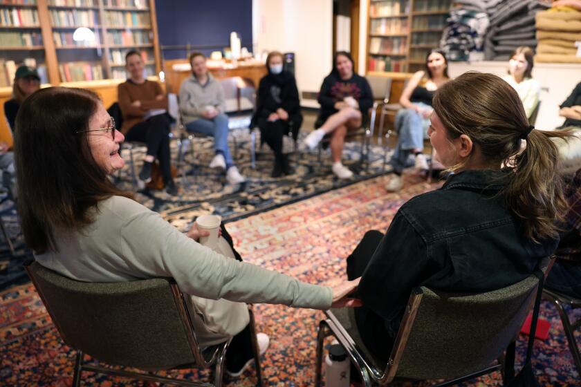 LOS ANGELES-CA-MAY 16, 2024: Elizabeth Lui, left, host of the death cafe at the Philosophical Research Society, reaches out to Haley Twist, 32, right, during a meeting in Los Feliz on May 16, 2024. (Christina House / Los Angeles Times)
