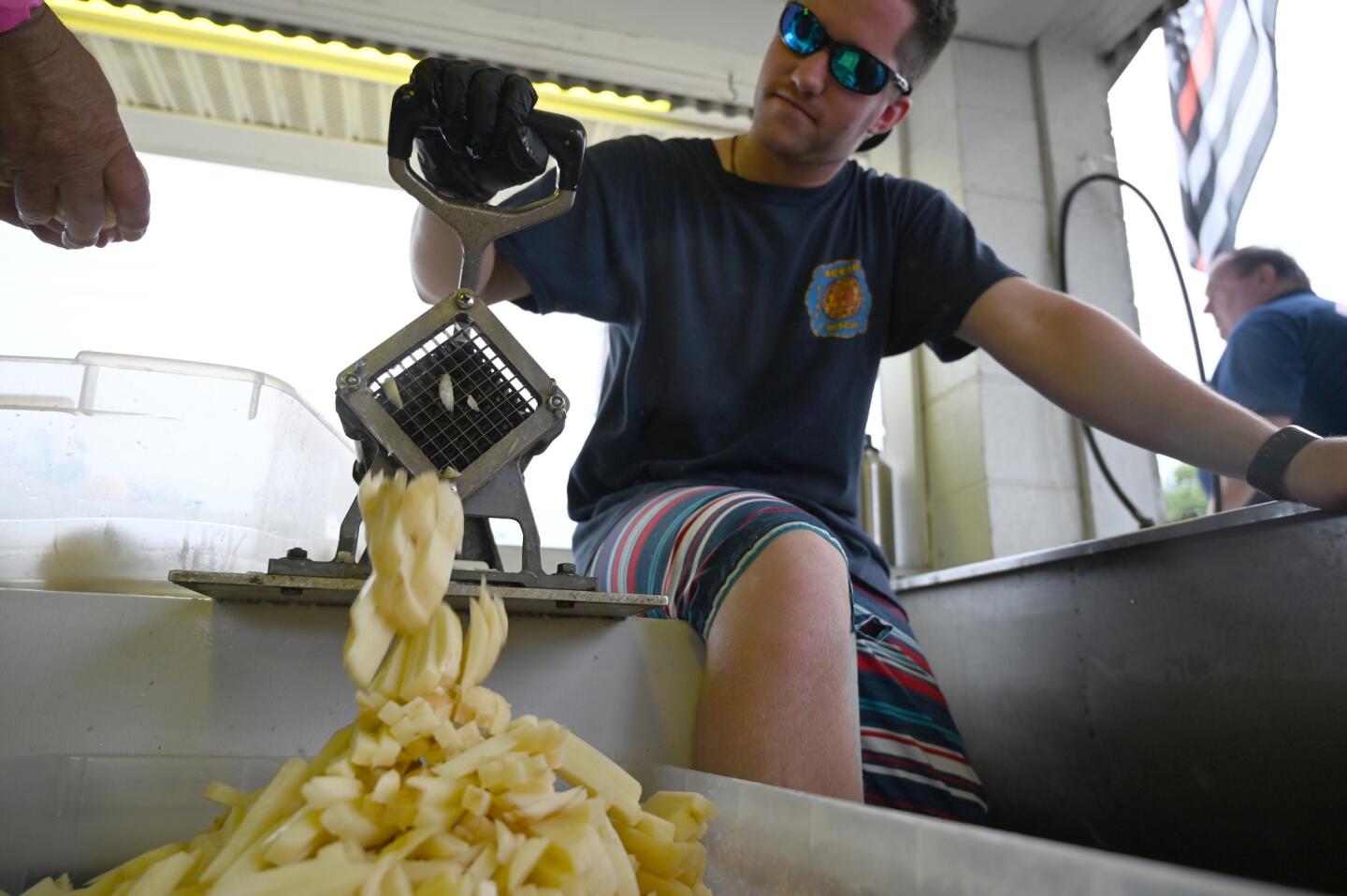 Haden Nugent works on cutting a bucket of peeled potatoes for the purpose of making fries during the carnival at Reese & Community Volunteer Fire Company on Tuesday, July 16.