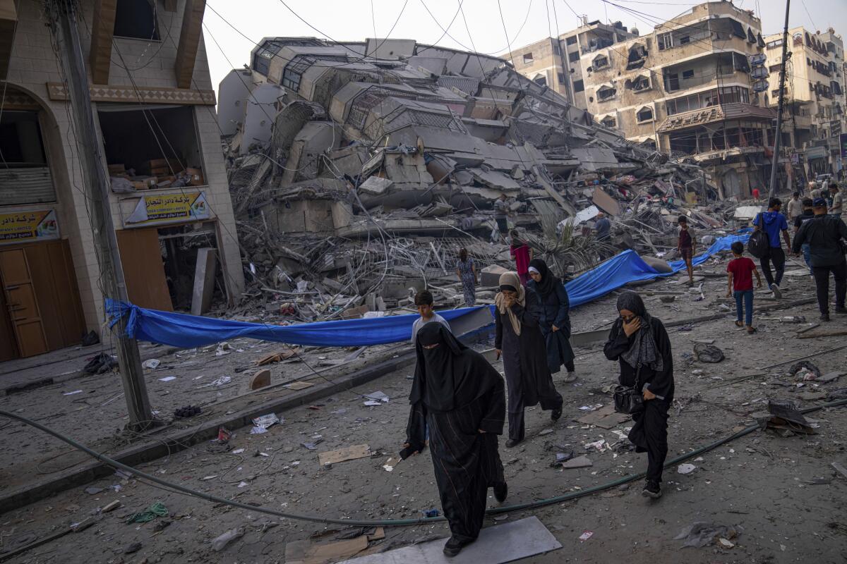 Palestinos caminan junto a un edificio en ruinas tras un ataque aéreo palestino en Ciudad de Gaza.