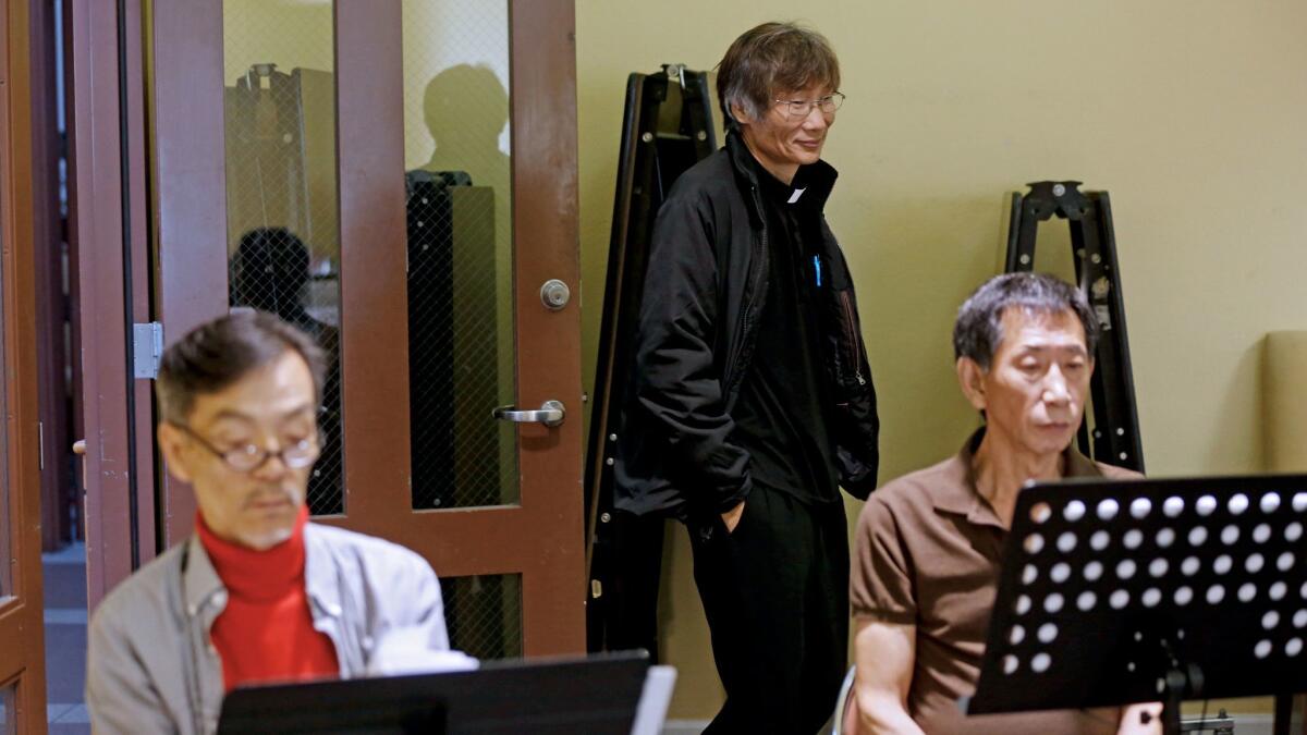 Seon Jin Kim, left, and the Rev. John Kim, center, are shown at choir practice at St. James Episcopal Church. Seon Jin Kim lives in an unofficial homeless shelter for Koreans run by the priest.