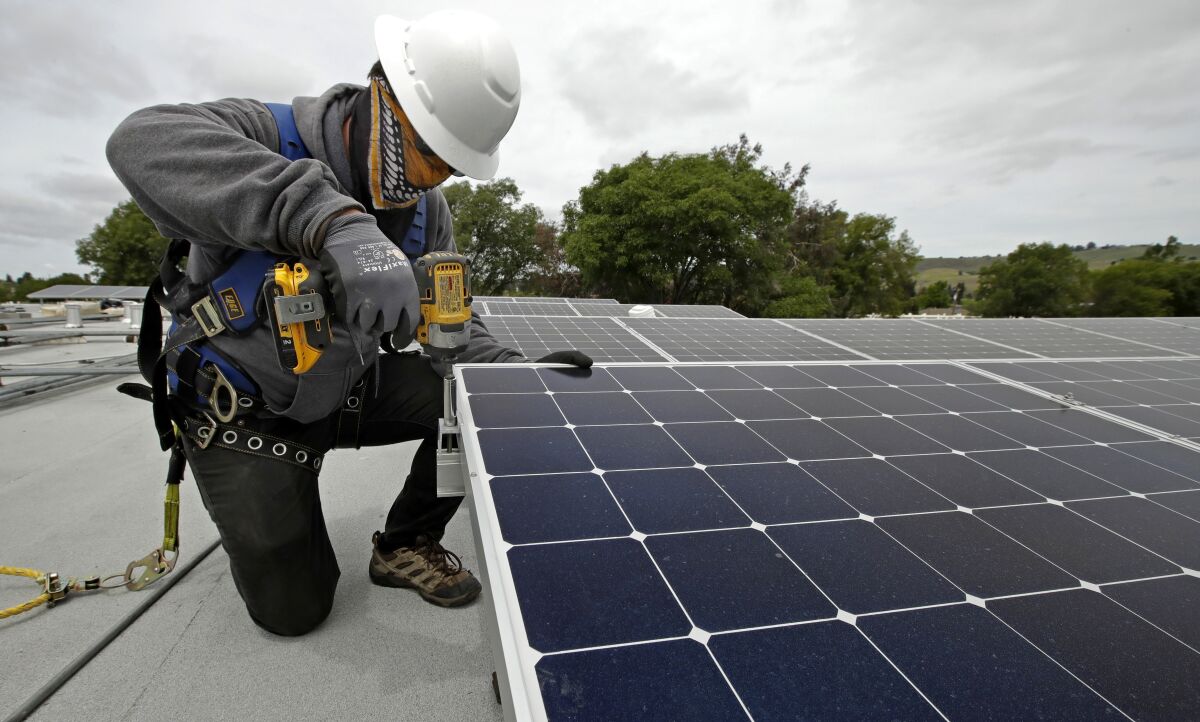 trabajadores instalan paneles solares en Hayward