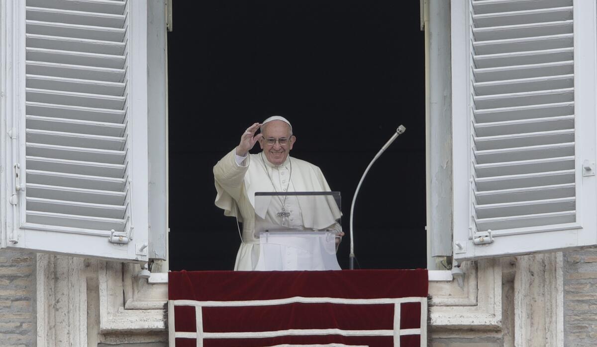 Pope Francis blesses the crowd as he recites the Angelus noon prayer from the window of his studio overlooking St. Peter's Square at the Vatican on Sunday.