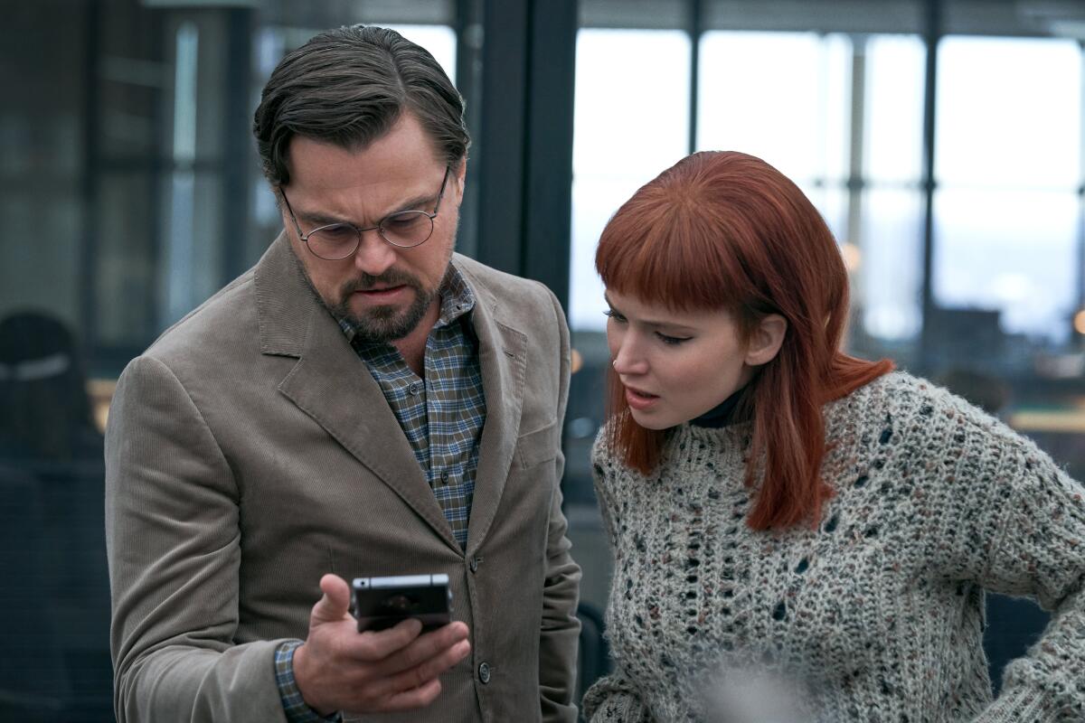 A man, left, and a woman look at a phone screen 