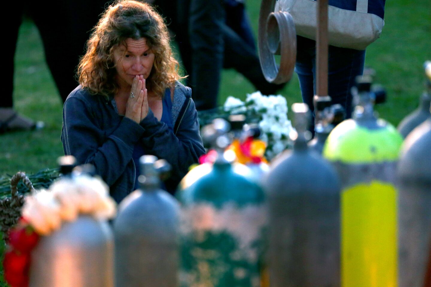 A mourner pays her respects at a memorial made up of scuba tanks, one for each victim, during the vigil at Chase Palm Park on Friday night.