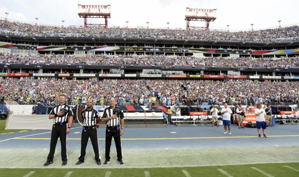 Officials stand on the sideline before a game between the Seattle Seahawks and the Tennessee Titans. Neither team came out onto the field for the anthem. (Mark Zaleski / Associated Press)