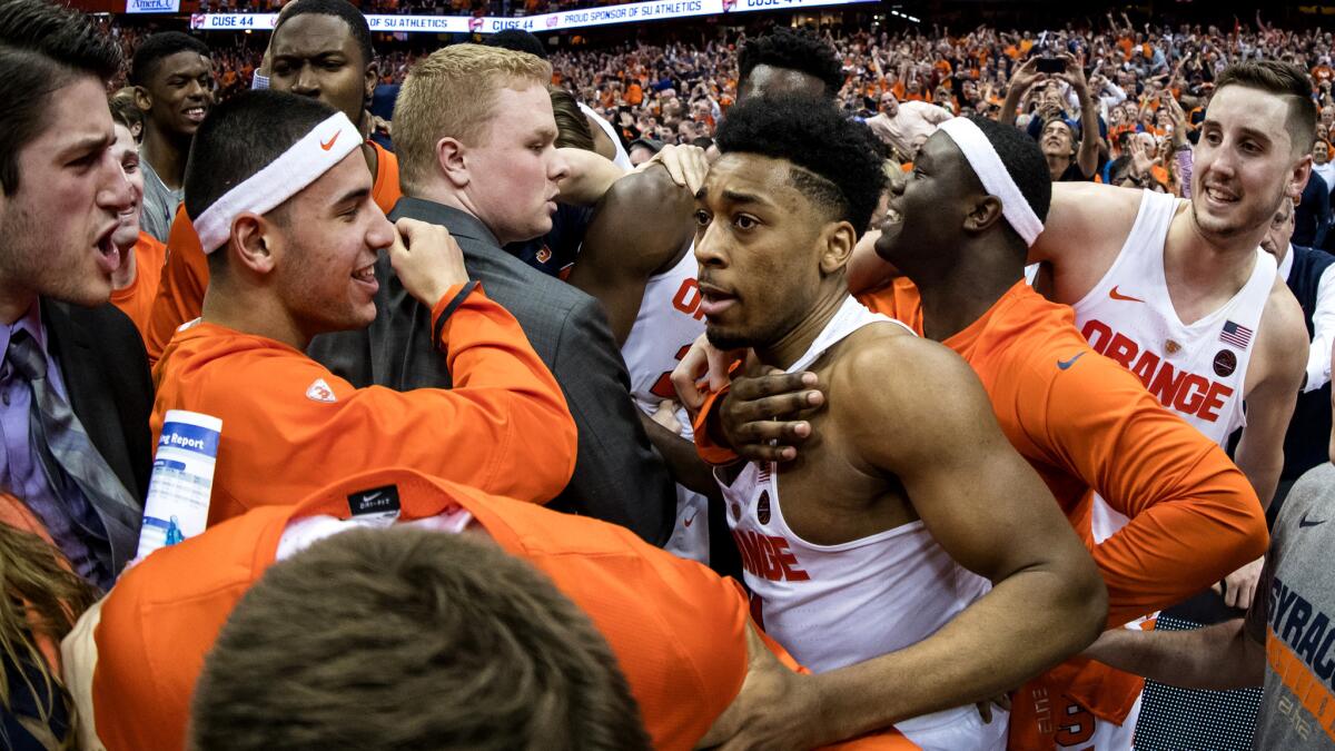 Syracuse teammates and fans swarm John Gillon after he made a buzzer-beating shot to defeat Duke on Wednesday night.