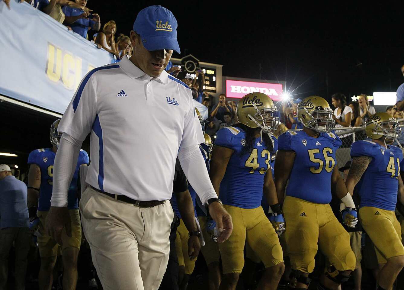 UCLA Coach Jim Mora leads the Bruins onto the field for their game against Houston on Saturday night at the Rose Bowl.
