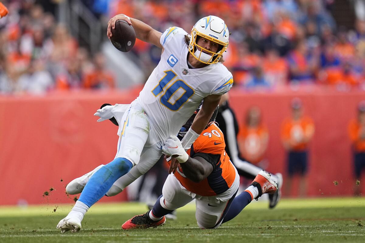 Chargers quarterback Justin Herbert (10) is pulled down by Denver Broncos defensive end DeShawn Williams.