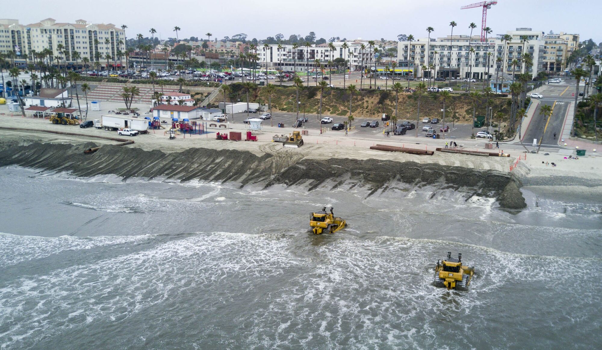 In May 2017, bulldozers pushed sand up onto the beach after it was pumped from the Oceanside harbor.